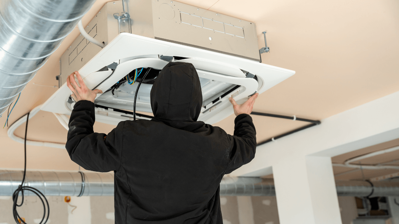 Technician installing ceiling ductwork for an air conditioning system