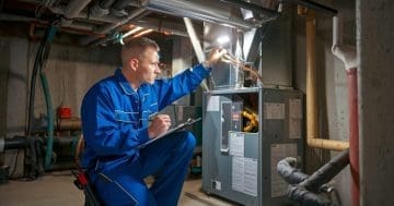 HVAC Technician Inspecting Furnace in Dimly Lit Basement