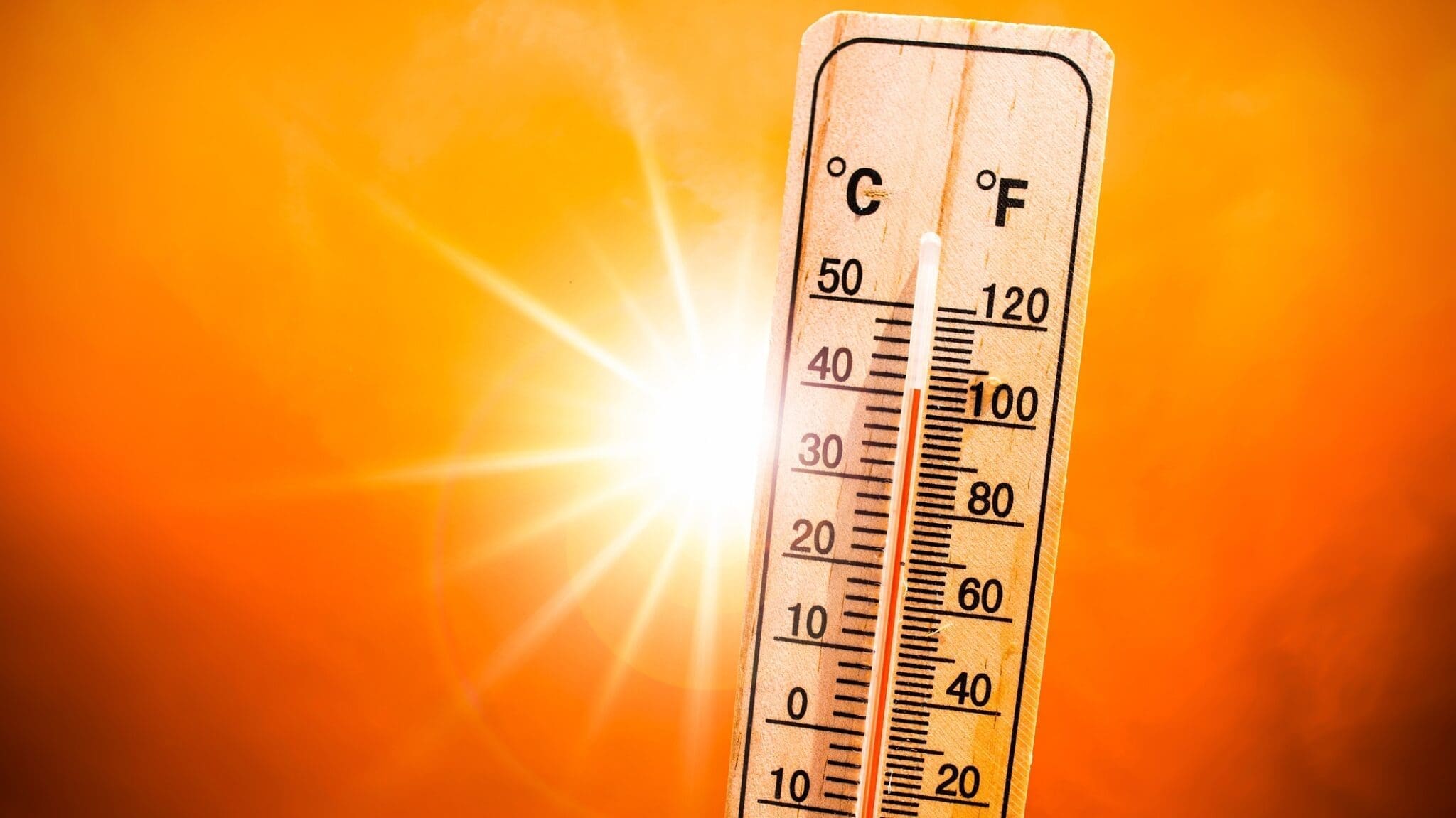 Thermometer showing heat measurement of over a hundred with the sun behind it